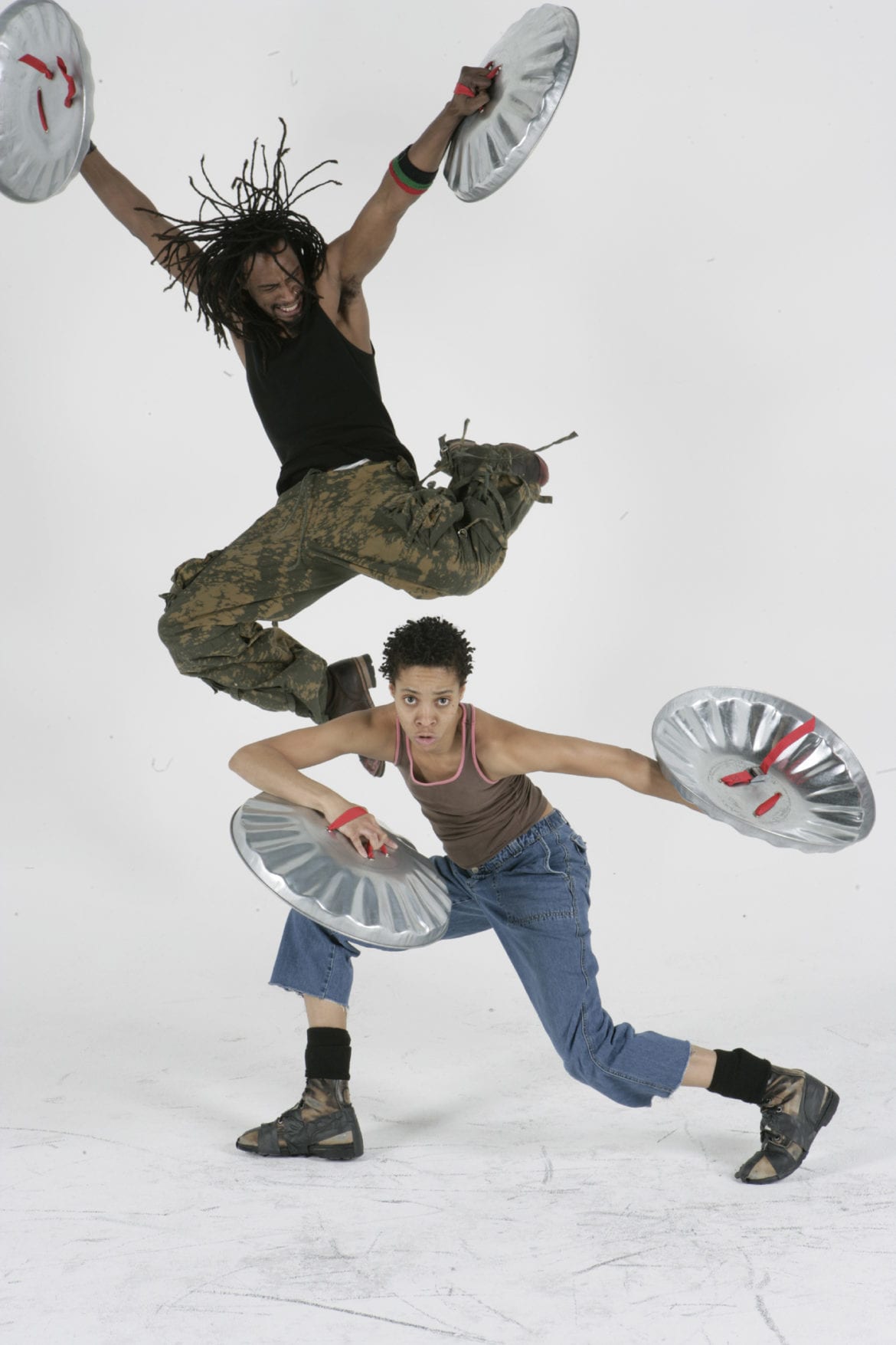 Two people dancing with trashcan lids.