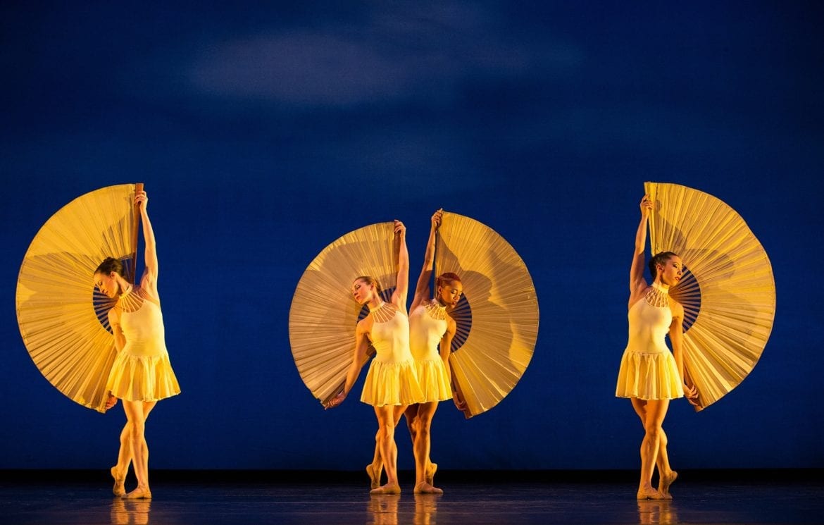 Four women in yellow costume posing against a blue backdrop.