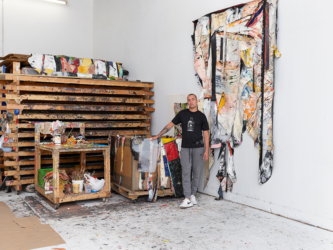 Angel Otero stands next to scrapped paintings