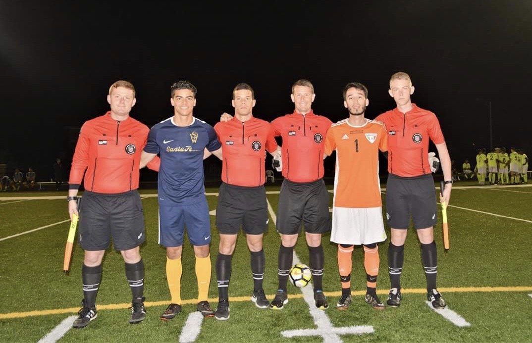 Soccer players, including Luis Cadena pose for a photo pre-match with referees.