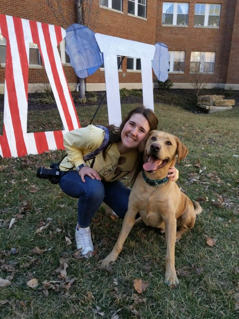 Maggie Mannebach, college student, smiles with her dog on campus.