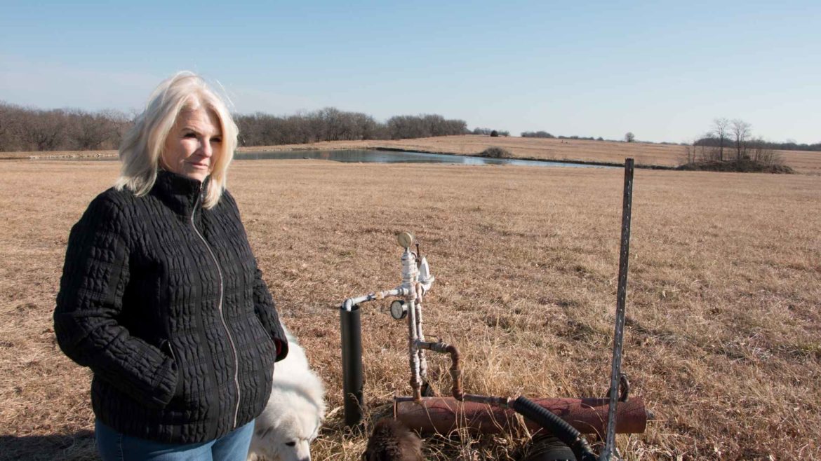 Connie Mayberry stands next to a gas well that roughly marks where development would begin behind her property.