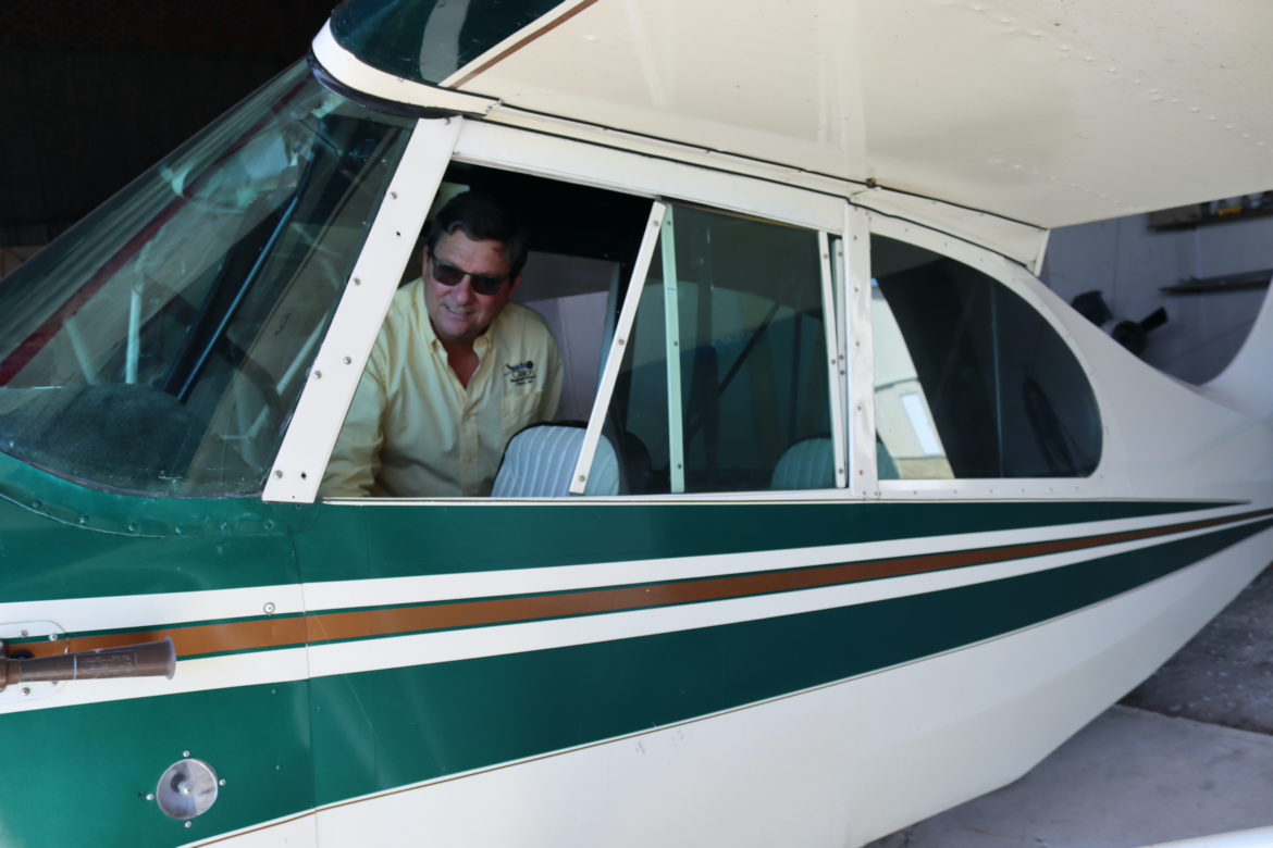 The man looks into the cockpit of a small two-seater plane.