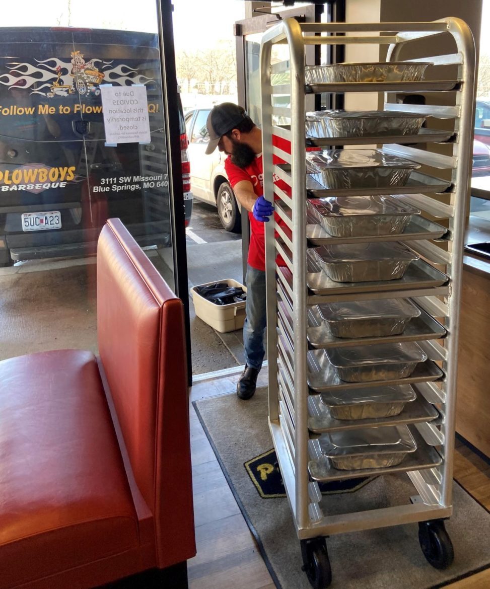 Plowboys Barbeque’s Justin Rieck rolls trays of family-style barbecue to the curbside for delivery to organizations and families in need.