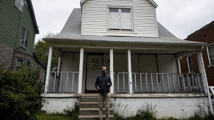 Gregg Lombardi stands in front of a home classified as a dangerous building in the Lykins Neighborhood of Kansas City, Missouri. The house is abandoned and situated in between two occupied homes.