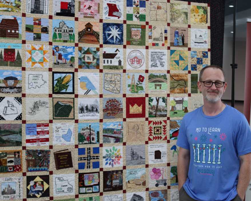 Michael Sweeney has driven the Missouri Bicentennial Quilt all around the state to make sure everyone can see it. Here he stands next to it at its exhibition in Columbia, Missouri.