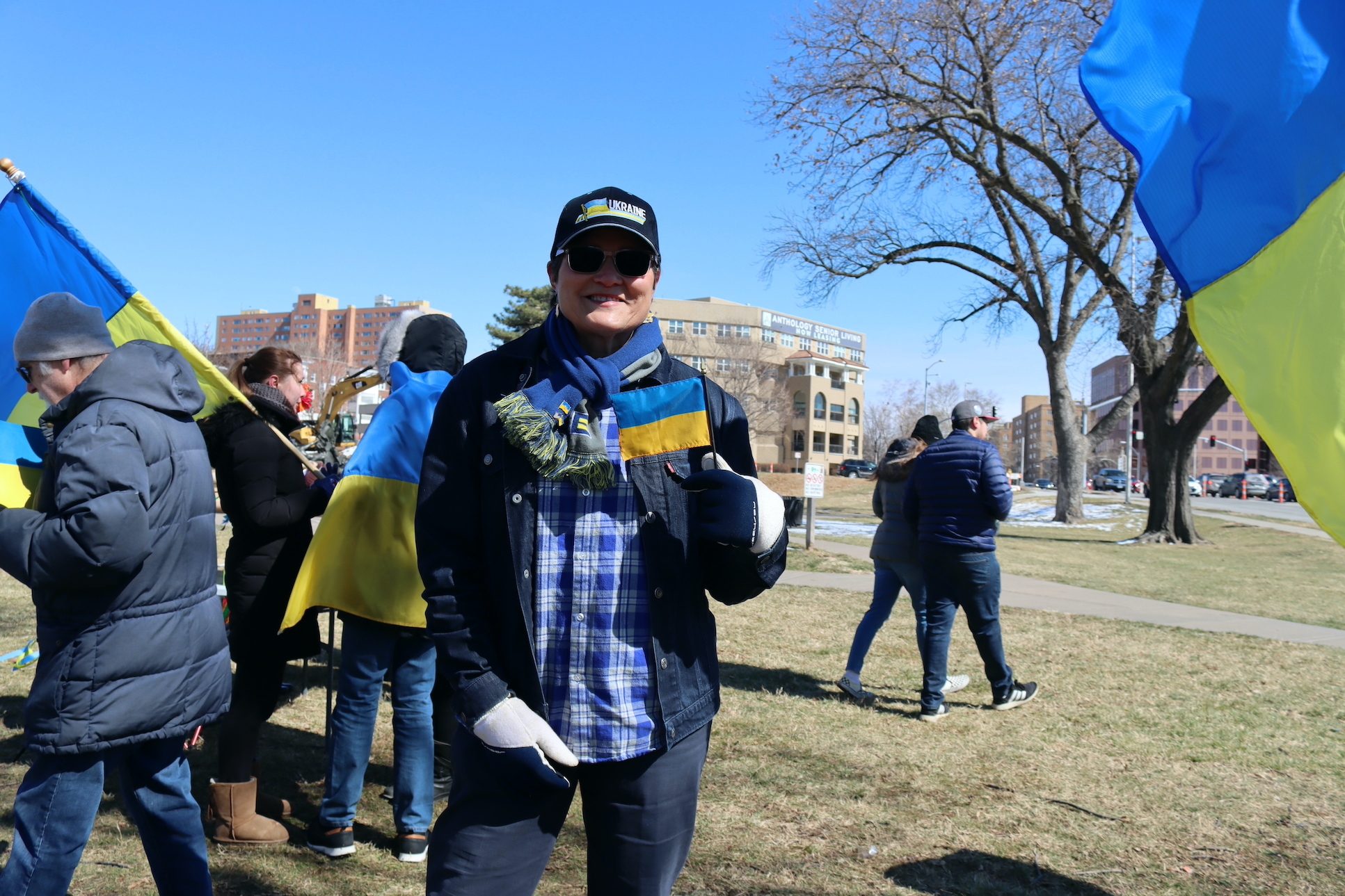 Woman holds small Ukrainian flag up. She sports a Ukraine cap.